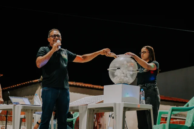 Apresentador e participante retirando uma bola do globo durante o sorteio